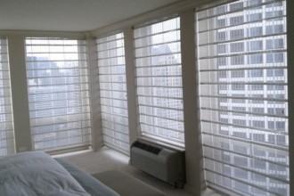 B&W Horizons Woven Wood Roman Shade with Hunter Douglas Motorized Blackout Roller Shades Behind